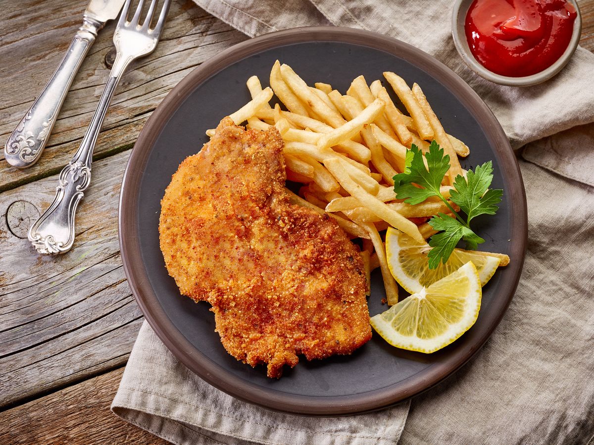 Schnitzel mit Pommes auf einem gedeckten Tisch